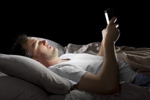 male in bed browsing the internet late at night with a tablet